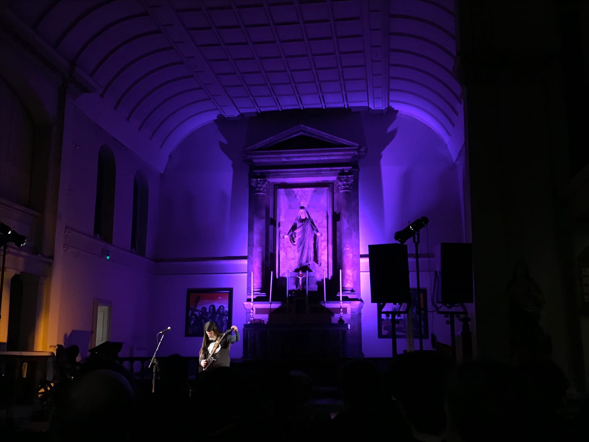 Dylan Carlson tuning his guitar in front of the altar at St John of Bethnal Green church, bathed in purple floodlights