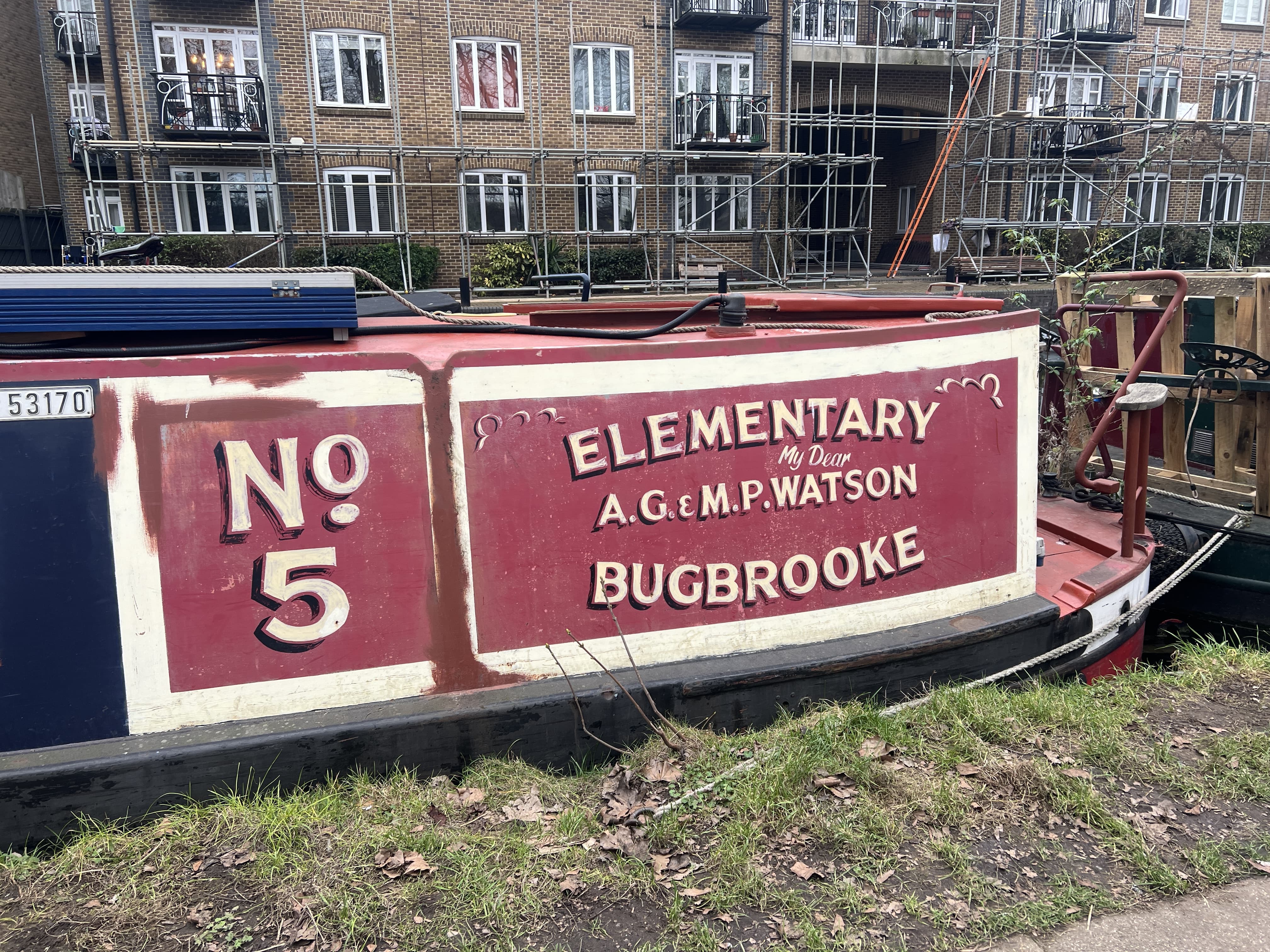 Narrowboat moored on the canal with handpainted signage